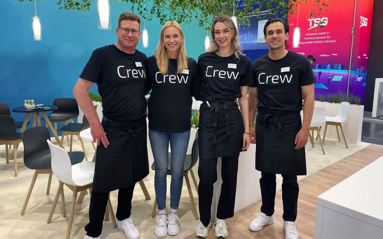 Vierköpfige Messecrew in schwarzen Crew-Shirts auf einem Messestand